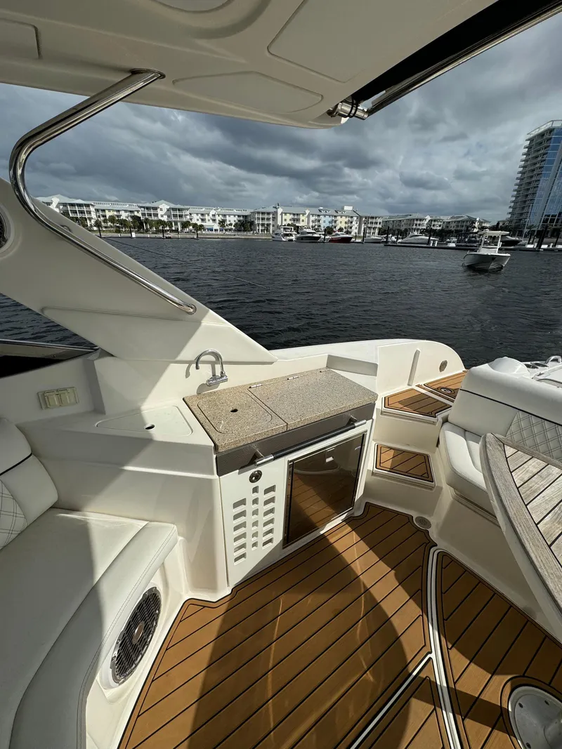 Slide: The Image of 2015 Sea Ray 350 SLX boat interior with waterfront view, featuring seating and kitchenette. - 10