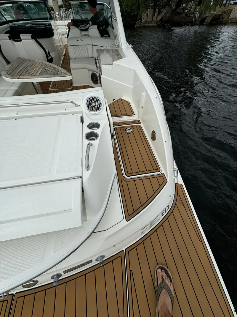 Slide: The Image of 2015 Sea Ray 350 SLX boat deck with teak flooring, docked by the water. - 19