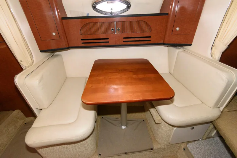Slide: The Image of 2005 Sea Ray 280 Sundancer cabin interior with wooden table and cushioned seating. - 8