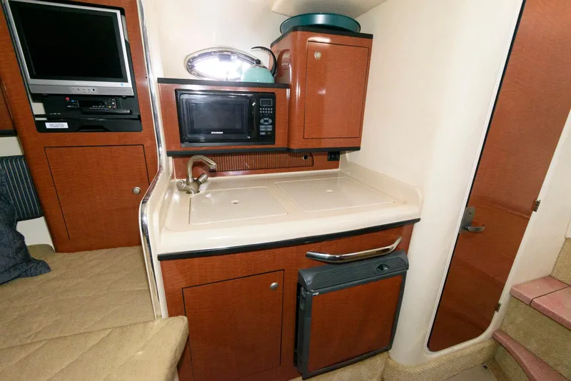 Slide: The Image of 2005 Sea Ray 280 Sundancer cabin kitchen with microwave, sink, and compact fridge. - 9