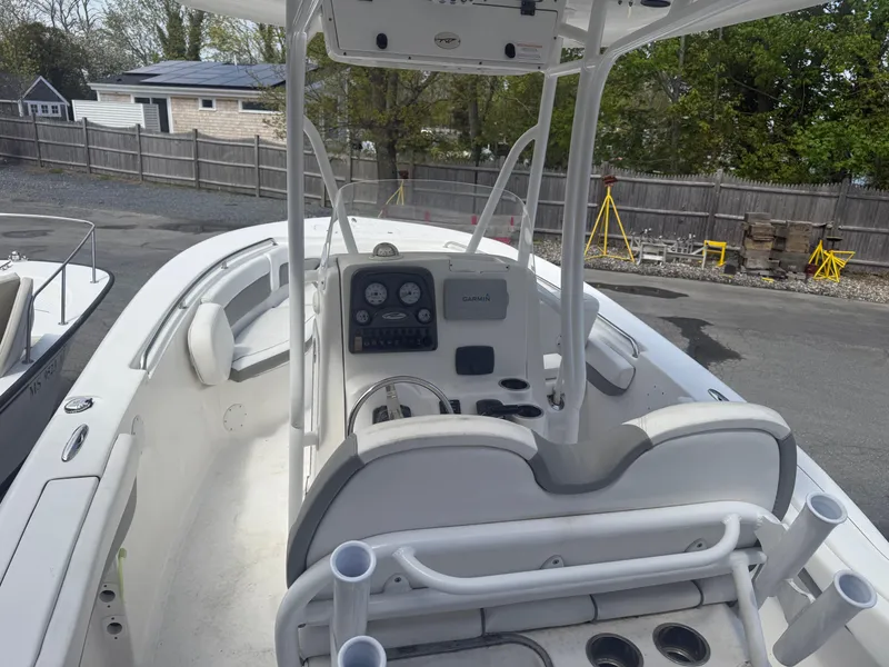 Slide: The Image of 2015 Tidewater 230 LXF boat interior with helm and seating, parked outdoors. - 5