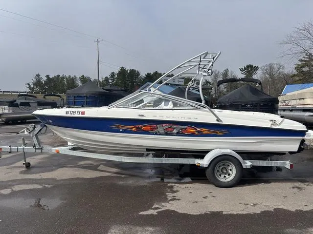Slide: The Image of 2006 Bayliner 205 MX boat on trailer with custom graphics, parked outdoors. - 1
