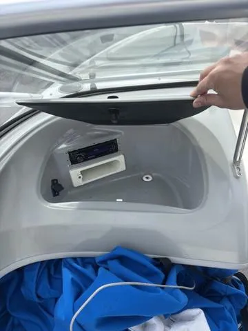 Slide: The Image of 2006 Bayliner 205 MX boat storage compartment with stereo system and blue cover. - 11