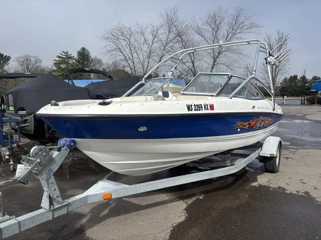Slide: The Image of 2006 Bayliner 205 MX boat on trailer, blue and white design, parked outdoors. - 2