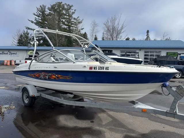 Slide: The Image of 2006 Bayliner 205 MX boat on trailer, parked outdoors near a blue-roofed building. - 4