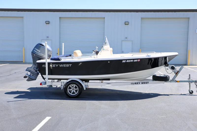 Slide: The Image of 2016 Key West 176 Center Console boat on trailer, parked outside a warehouse. - 0