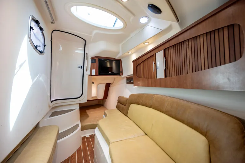 Slide: The Image of 2015 Grady-White Freedom 375 cabin interior with seating, TV, and wood accents. - 32