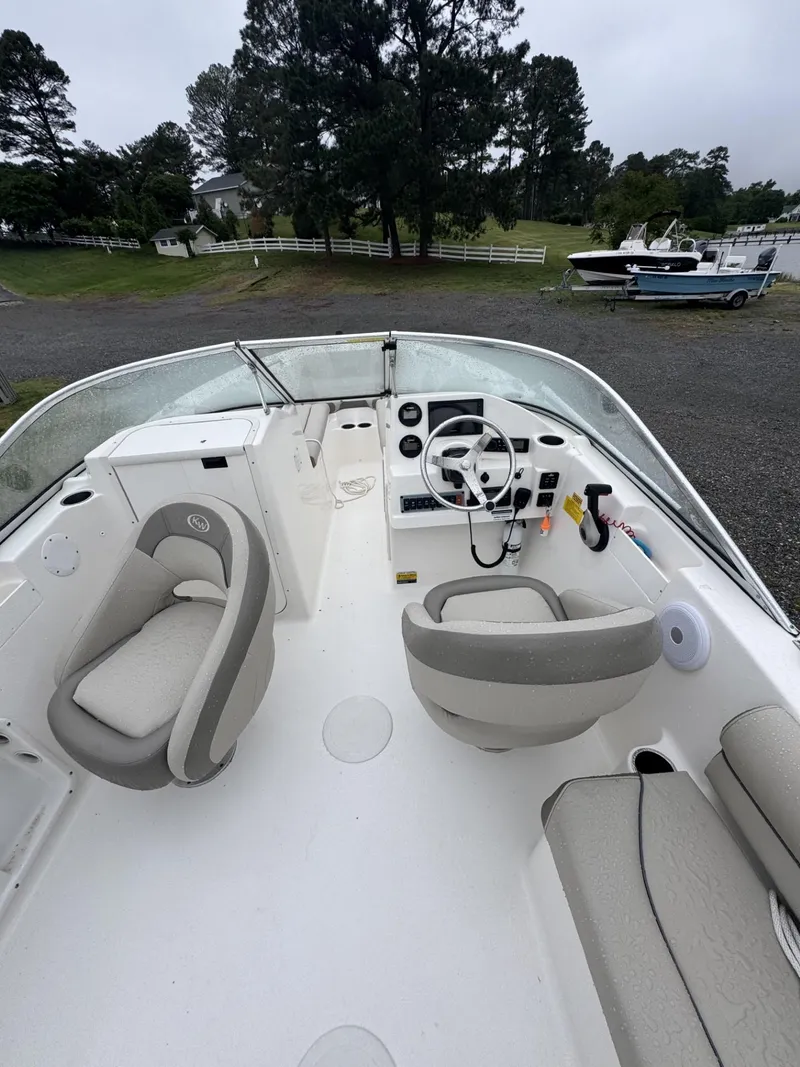Slide: The Image of 2021 Key West 203 DFS boat interior with steering wheel and seating, parked outdoors. - 4
