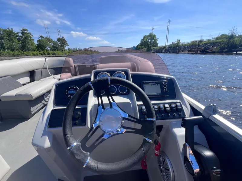 Slide: The Image of 2022 Sylvan Mirage 820 PARTY FISH boat interior with steering wheel and control panel on a sunny day. - 10