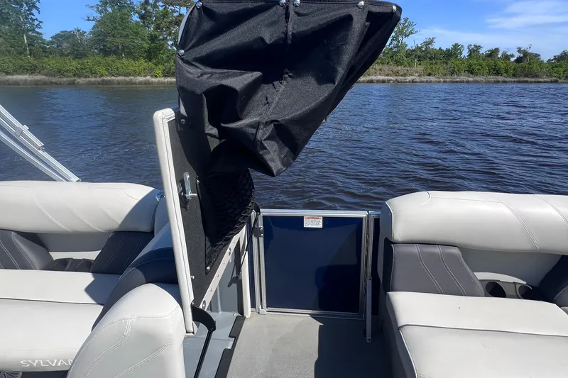 Slide: The Image of 2022 Sylvan Mirage 820 PARTY FISH pontoon boat interior with seating, on a calm lake. - 15
