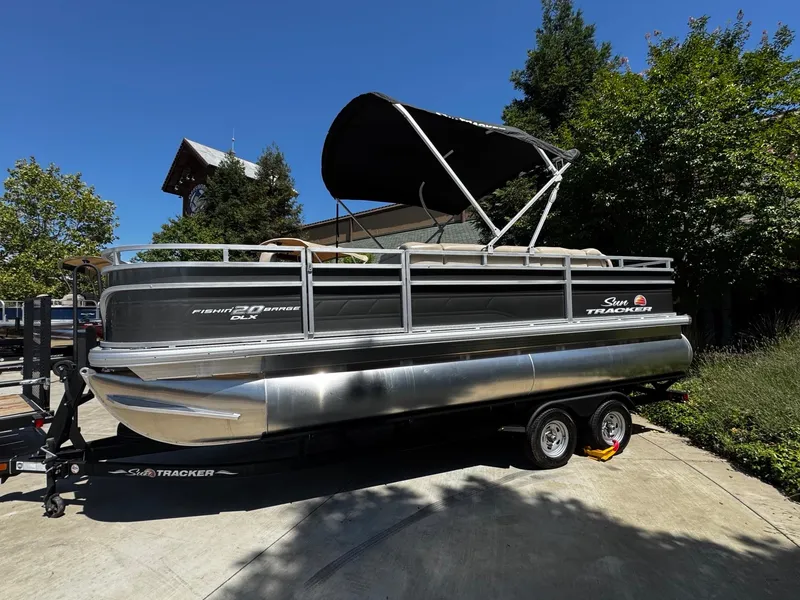 Slide: The Image of 2025 Sun Tracker Fishin' Barge 20 DLX pontoon boat on trailer, parked outdoors. - 3