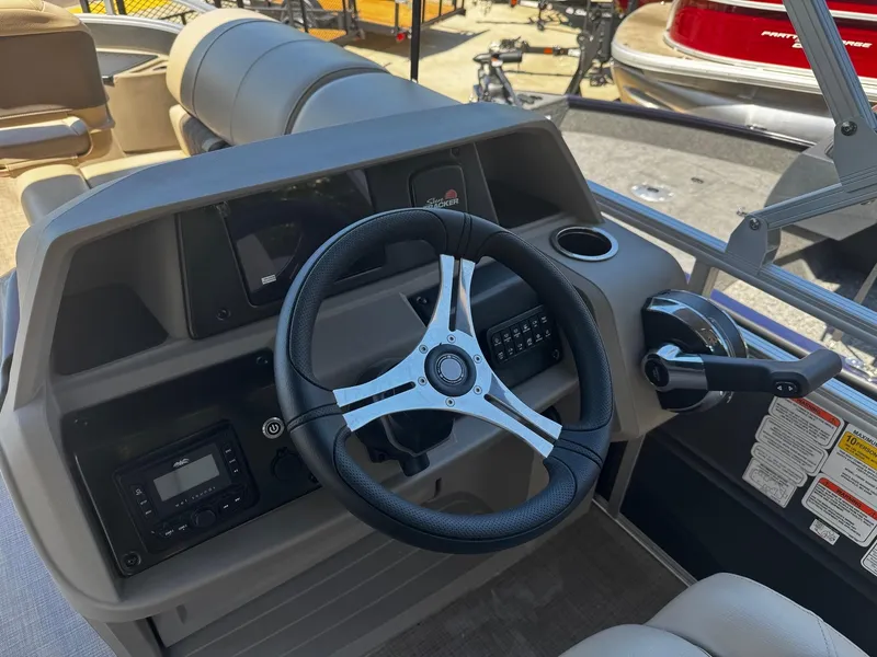 Slide: The Image of 2025 Sun Tracker Fishin' Barge 20 DLX steering console with controls and cup holder. - 4