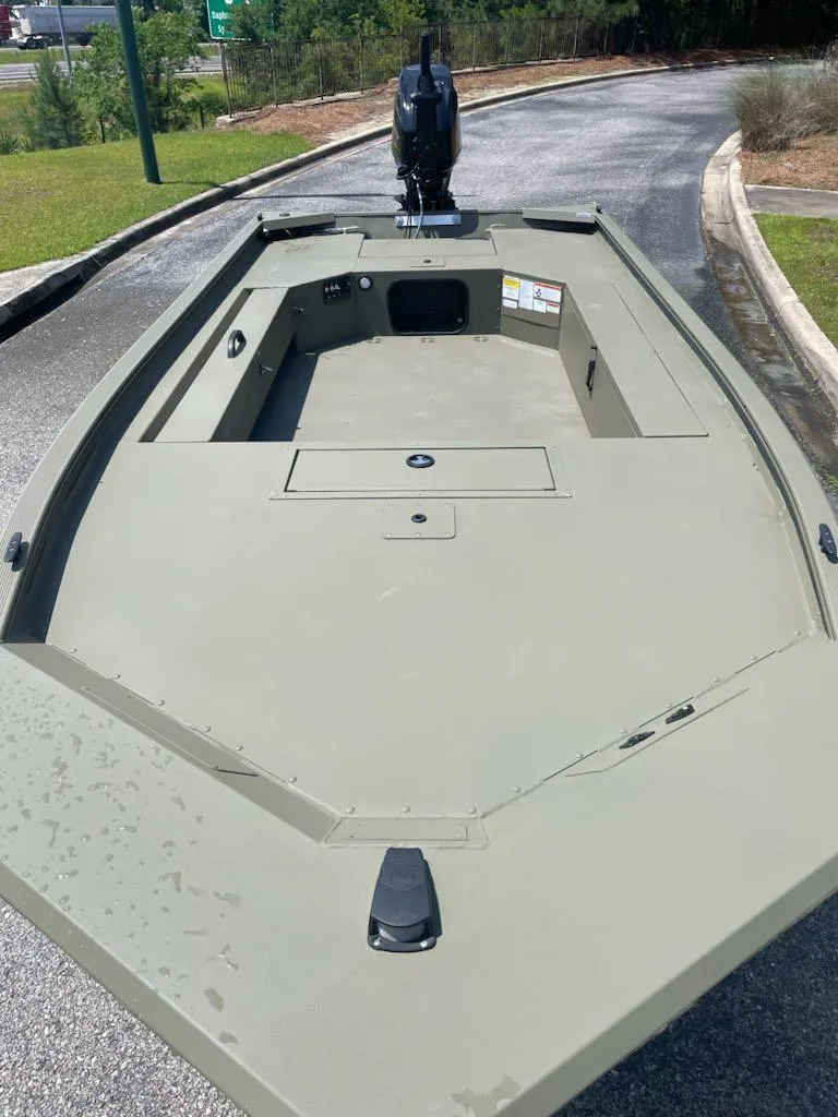 Slide: The Image of 2025 Tracker Grizzly 1654 T Sportsman boat, olive green, parked on a paved path. - 2