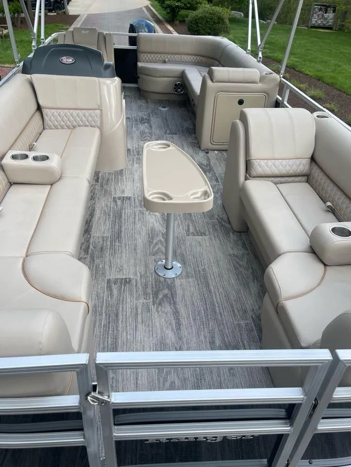 Slide: The Image of 2025 Ranger Reata 220C pontoon boat with beige seating and wood-style flooring. - 5