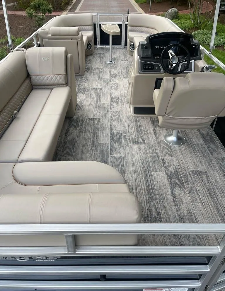 Slide: The Image of 2025 Ranger Reata 220C pontoon boat interior with beige seating and modern helm. - 6