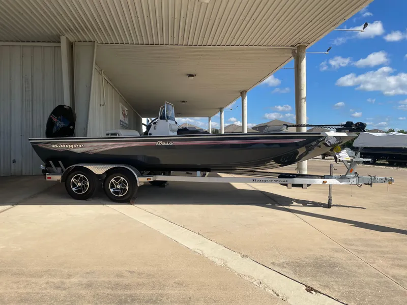 The Image of 2025 Ranger RB210 boat on trailer under a covered area, clear blue sky background. - 0