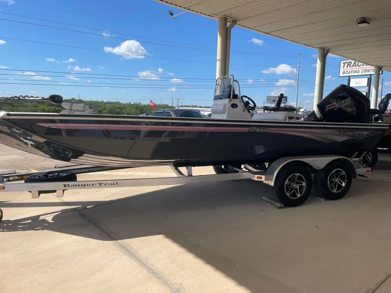 Slide: The Image of 2025 Ranger RB210 boat on trailer at dealership, under a canopy, clear sky background. - 4
