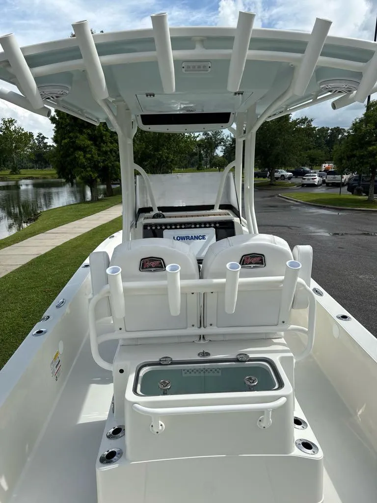 Slide: The Image of 2025 Ranger 2360 Bay boat interior with rod holders and seating, near a lake. - 4