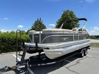 Slide: The Image of 2025 Sun Tracker Party Barge 22 DLX pontoon boat on trailer in parking lot. - 2