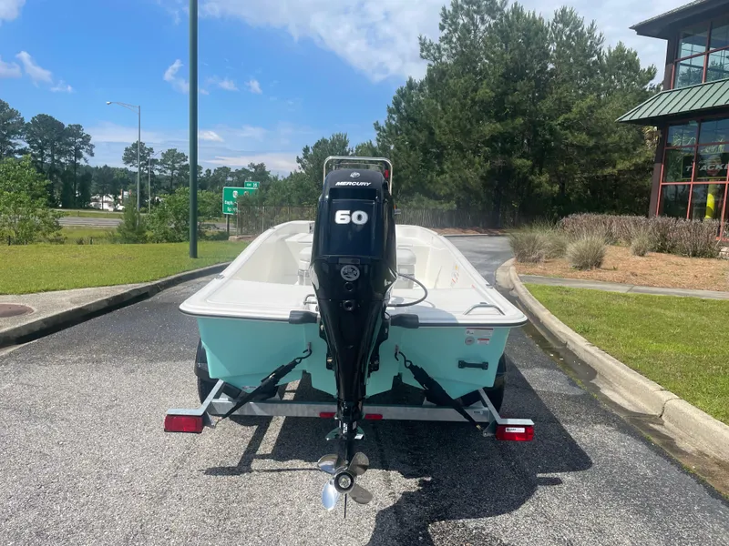 Slide: The Image of 2025 Mako Pro Skiff 15 CC boat with 60 HP engine on a trailer, parked outdoors. - 3