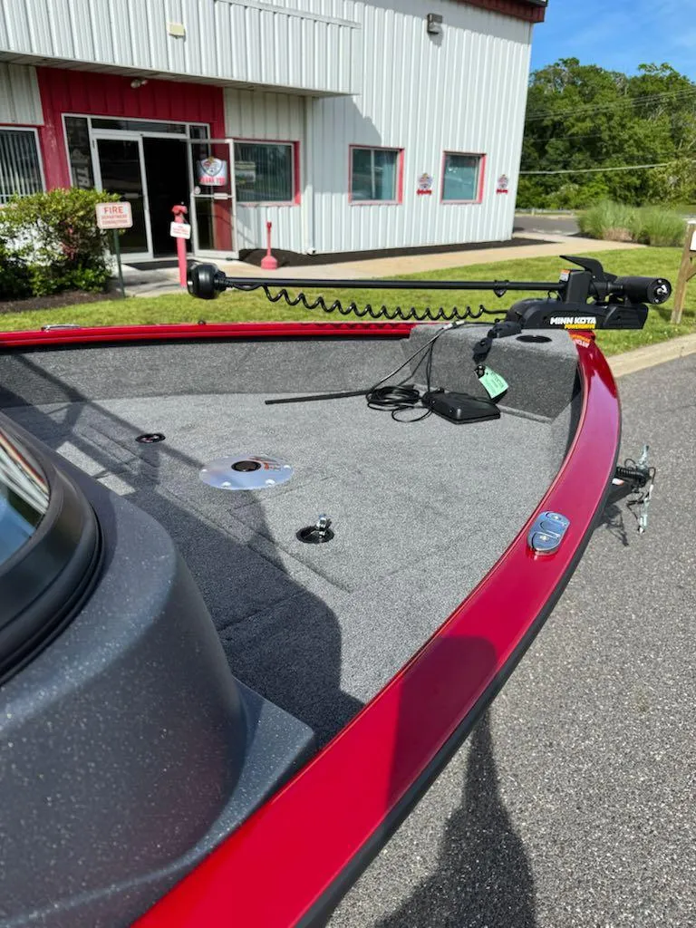 Slide: The Image of 2025 Tracker Pro Guide V-16 WT boat with trolling motor, parked outside a building. - 11