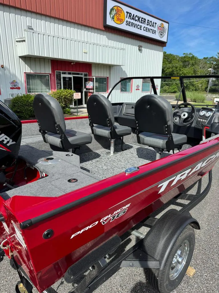 Slide: The Image of 2025 Tracker Pro Guide V-16 WT boat at service center, red exterior, three seats visible. - 7