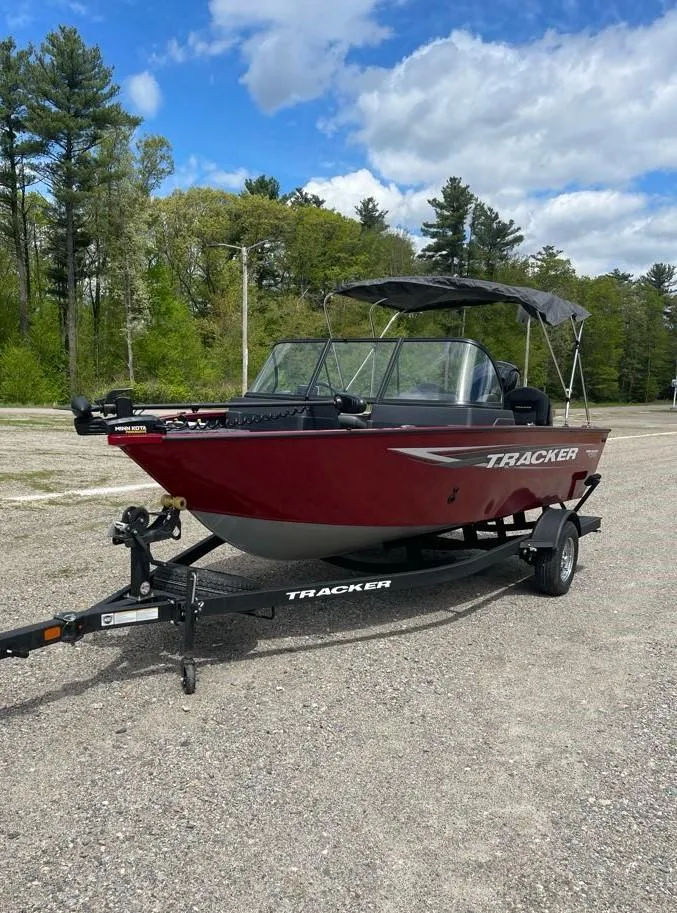 Slide: The Image of 2025 Tracker Pro Guide V-175 Combo boat on trailer, parked outdoors under a cloudy sky. - 2