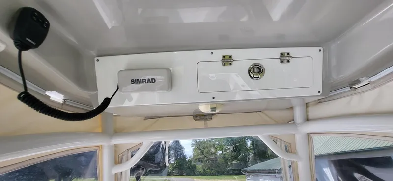 Slide: The Image of 2017 Sportsman Open 282 Center Console interior with Simrad equipment and storage compartment. - 19