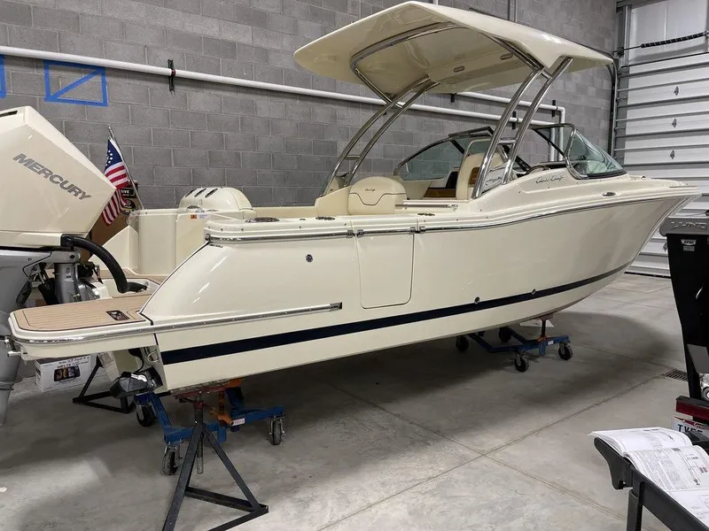 Slide: The Image of 2023 Chris-Craft 24 CALYPSO boat in a garage, featuring a sleek design and outboard motor. - 2