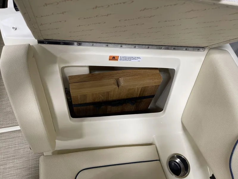 Slide: The Image of 2023 Chris-Craft 24 CALYPSO boat storage compartment with wooden panels and cushioned seating. - 24