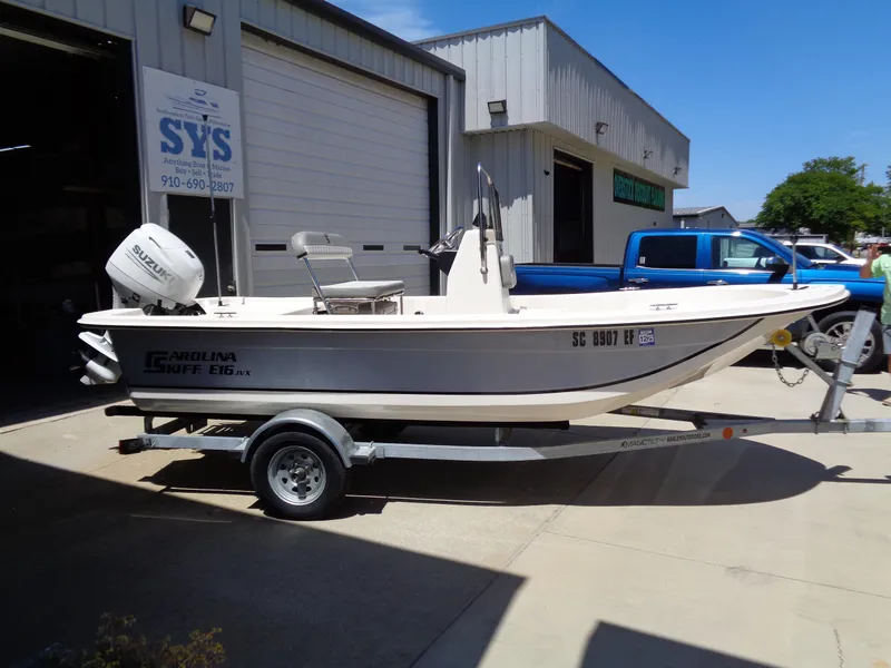 Slide: The Image of 2024 Carolina Skiff EL16JVX boat on trailer outside a garage. - 3