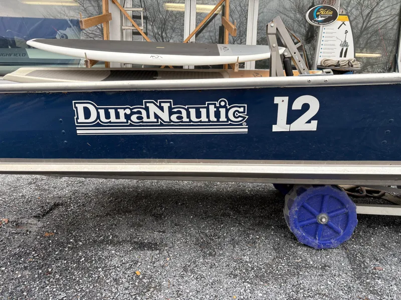 Slide: The Image of Duranautic 12 boat, 2021 model, parked on gravel with blue wheels. - 7