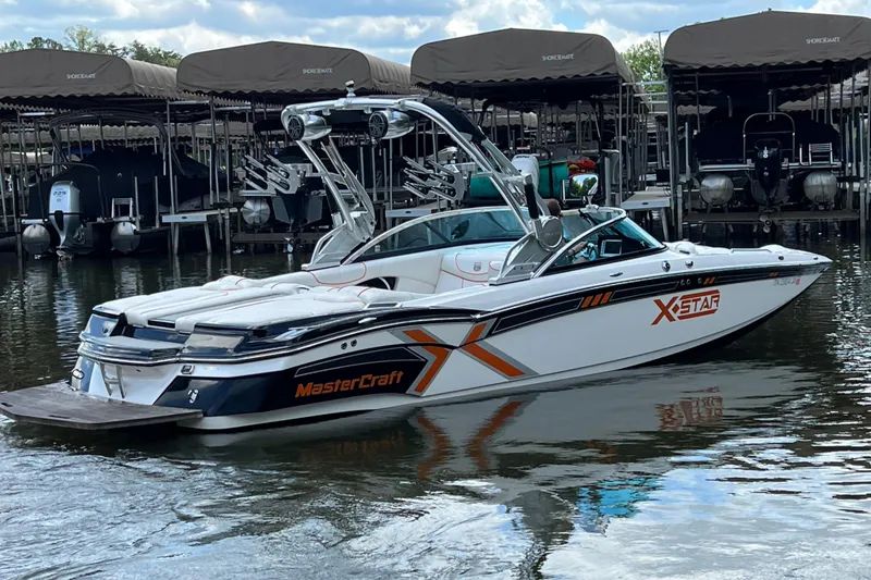 Slide: The Image of 2013 MasterCraft XStar boat docked on calm water, featuring sleek design and vibrant graphics. - 1