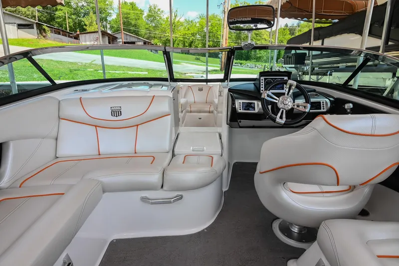 Slide: The Image of 2013 MasterCraft XStar boat interior with white and orange seating, modern dashboard, and steering wheel. - 14