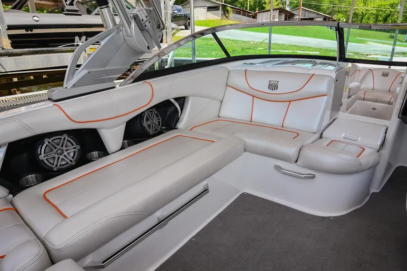 Slide: The Image of 2013 MasterCraft XStar boat interior with white and orange seating, featuring built-in speakers. - 19