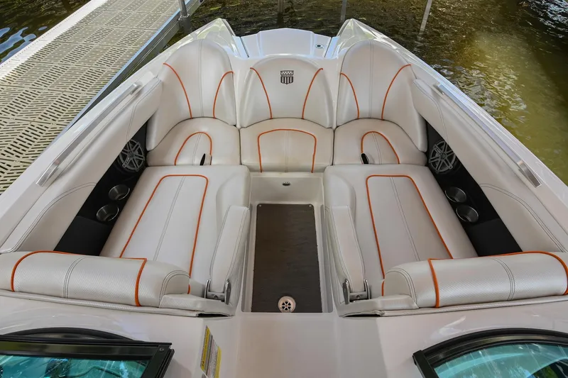 Slide: The Image of 2013 MasterCraft XStar boat interior with white and orange seating, docked by the water. - 29