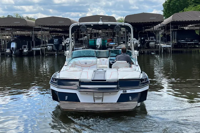 Slide: The Image of 2013 MasterCraft XStar boat docked on a calm lake under cloudy skies. - 3