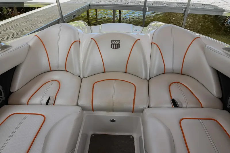 Slide: The Image of 2013 MasterCraft XStar boat interior with white and orange seating, docked by the water. - 31