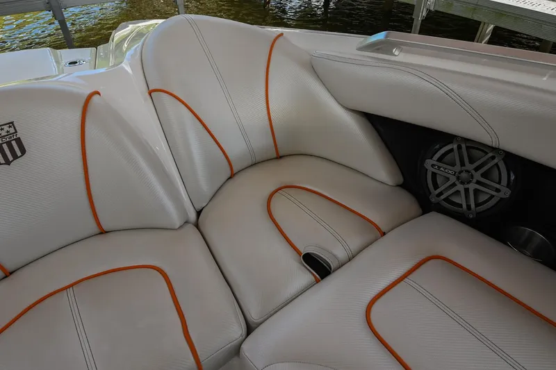 Slide: The Image of 2013 MasterCraft XStar interior with white and orange upholstery, featuring a speaker and cup holder. - 32