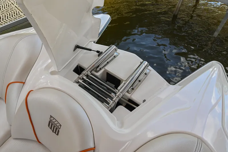 Slide: The Image of 2013 MasterCraft XStar boat with open storage compartment and ladder by the water. - 37