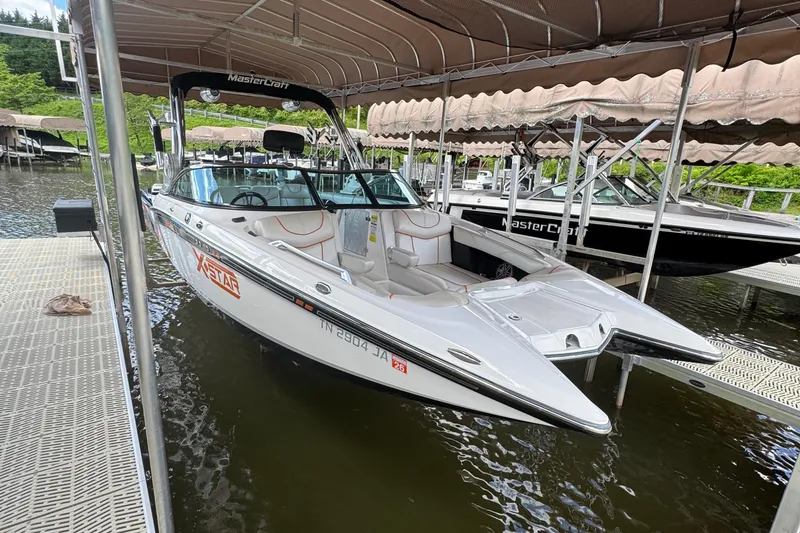 Slide: The Image of 2013 MasterCraft XStar boat docked under canopy on a lake. - 6