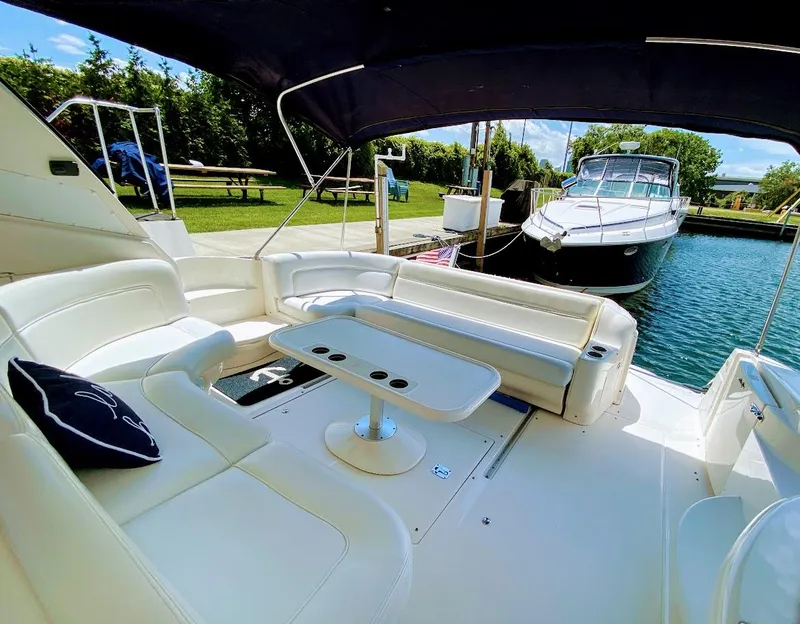 Slide: The Image of Luxurious 2001 Sea Ray 460 Sundancer yacht interior with white seating and table, docked by the water. - 15