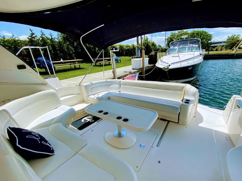 Slide: The Image of 2001 Sea Ray 460 Sundancer yacht interior with white seating and table, docked by the water. - 19
