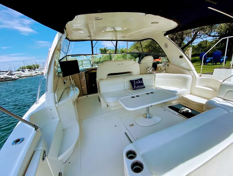 Slide: The Image of 2001 Sea Ray 460 Sundancer yacht interior with white seating and table, docked by the water. - 20