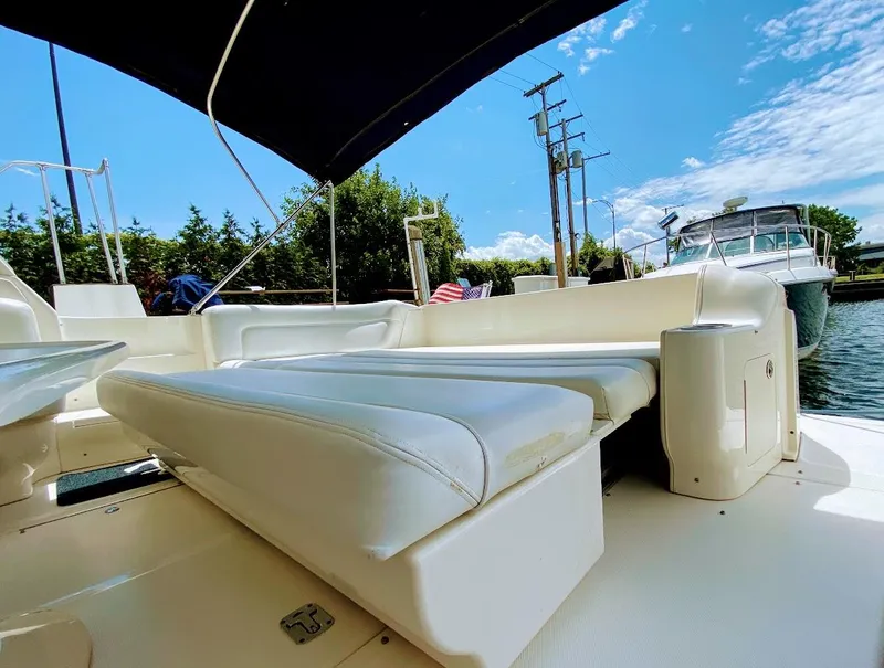 Slide: The Image of 2001 Sea Ray 460 Sundancer yacht interior with white seating and canopy, docked by the water. - 21