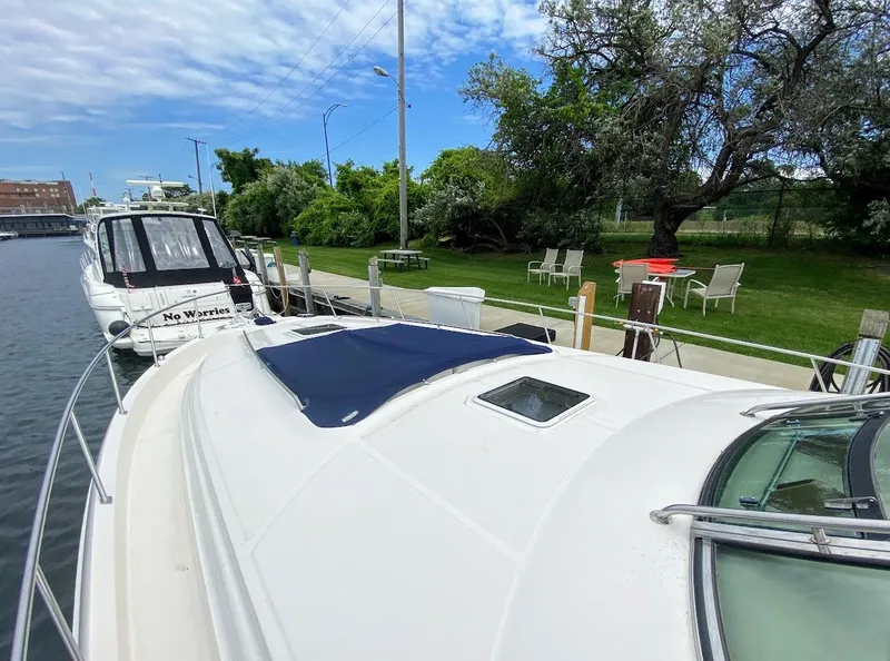 Slide: The Image of 2001 Sea Ray 460 Sundancer docked near a grassy area with chairs and trees. - 39