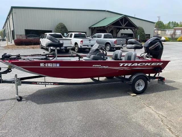 The Image of 2022 Tracker PRO170 boat on trailer, red color, parked near industrial building. - 0