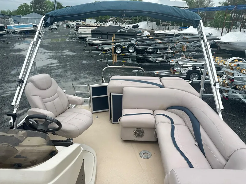Slide: The Image of 2015 Godfrey Sweetwater 20PE pontoon boat with beige seating and blue canopy in a marina. - 7