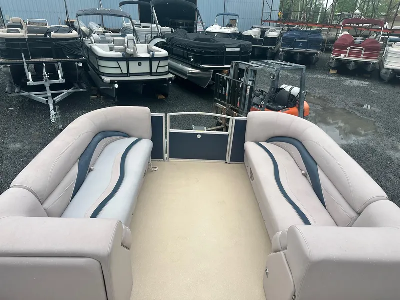 Slide: The Image of 2015 Godfrey Sweetwater 20PE pontoon boat interior with beige seating, parked among other boats. - 8