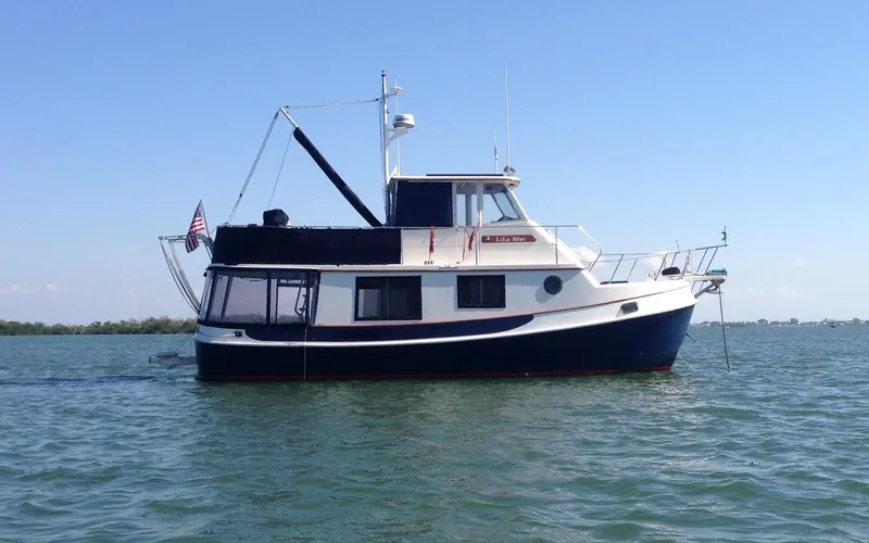 Slide: The Image of 1989 Kadey-Krogen Manatee 36 yacht on calm water, blue sky background. - 2